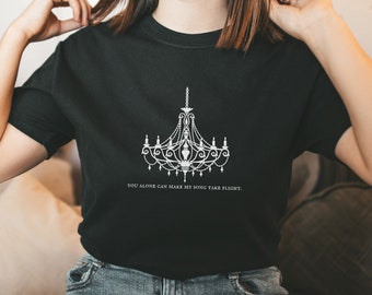 May include: A black t-shirt with a white graphic of a chandelier and the text "You alone can make my song take flight."