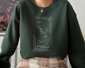 May include: A dark green sweatshirt with a white line drawing of two faces and the text "help me make the music of the night".