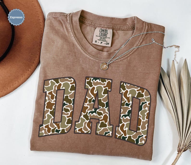 Cool and rugged Camo Dad Shirt designed for the ultimate Hunting Dad—perfect as a New Dad Father's Day Gift or Dad Birthday Gift. This comfortable and stylish Camouflage Dad Shirt makes a great Gift for Dad who loves the outdoors. A must-have Dad Tee for everyday wear, this Dad Tshirt is a top pick for any proud papa. Whether you're shopping for a Dad Gift or the Best Dad Gift, this shirt delivers both style and sentiment.