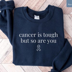 "Cancer is tough but so are you" in a simple text lettering. This Cancer awareness shirt is perfect for healthcare heroes or anyone supporting Breast Cancer Awareness, childhood cancer, cervical cancer and more. Makes a great oncology Nurse Tee or Nurse Tshirt for October events, hospital shifts, cancer encouragement shirt or cancer awareness walks. Show them their fight is out fight with this cancer Ribbon Shirt, not just for nurses or medical assistants.