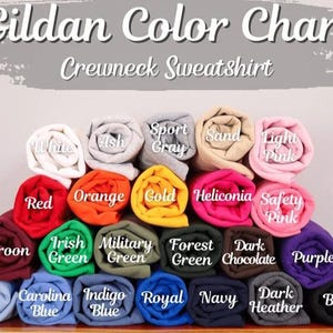May include: A color chart for Gildan crewneck sweatshirts. The chart displays a variety of rolled-up fabric samples in colors such as white, red, orange, gold, and purple. The text "Gildan Color Chart Crewneck Sweatshirt" is at the top.