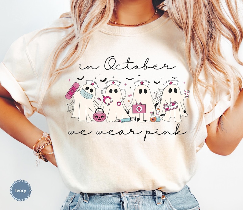 Pink Ghost Nurse Shirt featuring adorable ghost nurses with pink nurse stethoscopes and nurse items, with the phrase "In October We Wear Pink" in a script lettering. This Halloween Tee is perfect for healthcare heroes supporting Breast Cancer Awareness during spooky season. A thoughtful and festive Oncology Nurse Tee or Cute Nurse Tshirt for October events, hospital shifts, or awareness walks. Celebrate with this Pink Ribbon Shirt designed for nurses or medical assistants who care.