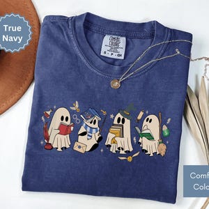 Halloween shirt featuring a cute reading ghosts dressed as wizard houses, perfect for spooky season. This wizard shirt doubles as a fun wizarding school tee or Halloween tee, ideal for Halloween matching, family trips, or Halloween group outfits with a magical twist.