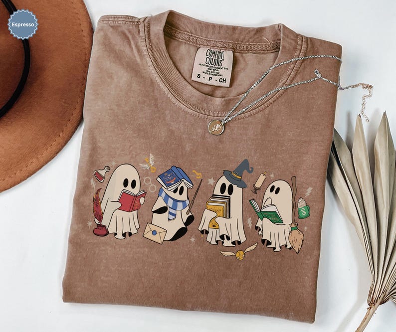 Halloween ghost shirt featuring four cute reading ghosts dressed as magical wizard characters with books, broomstick, owl, potion, and spooky season graphics on a cozy Halloween graphic tee.