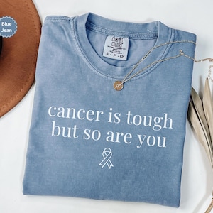 "Cancer is tough but so are you" in a simple text lettering. This Cancer awareness shirt is perfect for healthcare heroes or anyone supporting Breast Cancer Awareness, childhood cancer, cervical cancer and more. Makes a great oncology Nurse Tee or Nurse Tshirt for October events, hospital shifts, cancer encouragement shirt or cancer awareness walks. Show them their fight is out fight with this cancer Ribbon Shirt, not just for nurses or medical assistants.