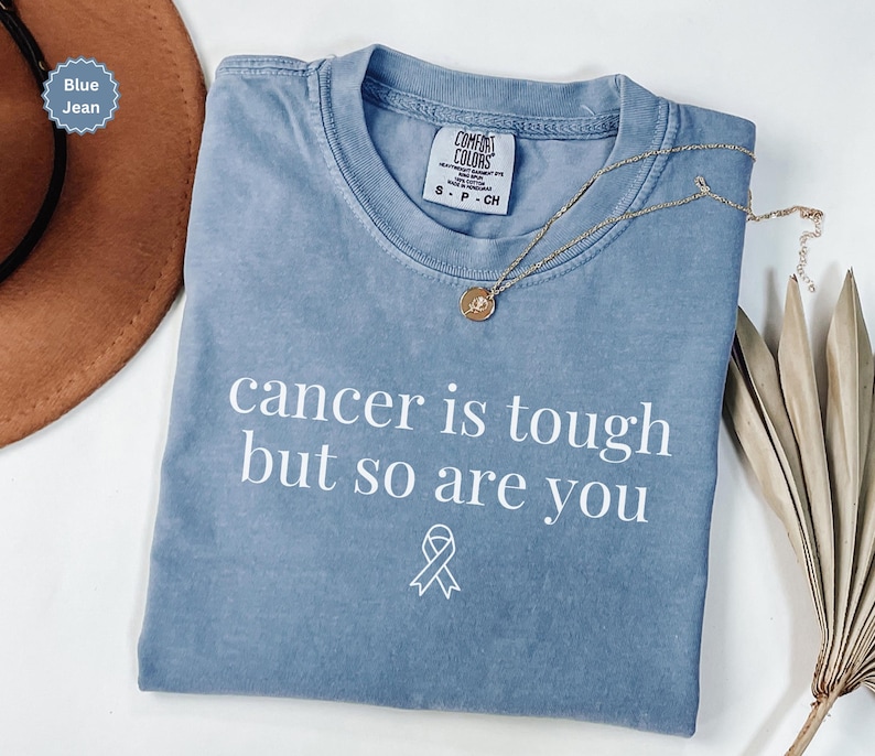 "Cancer is tough but so are you" in a simple text lettering. This Cancer awareness shirt is perfect for healthcare heroes or anyone supporting Breast Cancer Awareness, childhood cancer, cervical cancer and more. Makes a great oncology Nurse Tee or Nurse Tshirt for October events, hospital shifts, cancer encouragement shirt or cancer awareness walks. Show them their fight is out fight with this cancer Ribbon Shirt, not just for nurses or medical assistants.