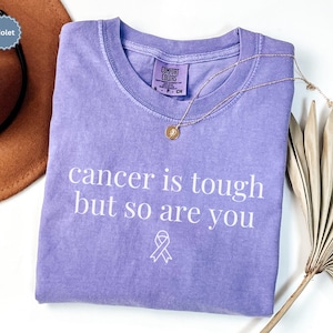 "Cancer is tough but so are you" in a simple text lettering. This Cancer awareness shirt is perfect for healthcare heroes or anyone supporting Breast Cancer Awareness, childhood cancer, cervical cancer and more. Makes a great oncology Nurse Tee or Nurse Tshirt for October events, hospital shifts, cancer encouragement shirt or cancer awareness walks. Show them their fight is out fight with this cancer Ribbon Shirt, not just for nurses or medical assistants.