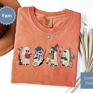 Halloween shirt featuring a cute reading ghosts dressed as wizard houses, perfect for spooky season. This wizard shirt doubles as a fun wizarding school tee or Halloween tee, ideal for Halloween matching, family trips, or Halloween group outfits with a magical twist.