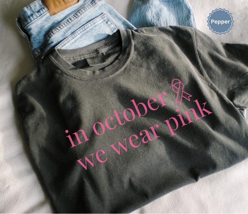 In October We Wear Pink in a simple lettering. This Halloween Tee is perfect for healthcare heroes or anyone supporting Breast Cancer Awareness during spooky season. A thoughtful and festive Oncology Nurse Tee or Cute Nurse Tshirt for October events, hospital shifts, or awareness walks. Celebrate with this Pink Ribbon Shirt designed for nurses or medical assistants who care.