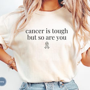"Cancer is tough but so are you" in a simple text lettering. This Cancer awareness shirt is perfect for healthcare heroes or anyone supporting Breast Cancer Awareness, childhood cancer, cervical cancer and more. Makes a great oncology Nurse Tee or Nurse Tshirt for October events, hospital shifts, cancer encouragement shirt or cancer awareness walks. Show them their fight is out fight with this cancer Ribbon Shirt, not just for nurses or medical assistants.