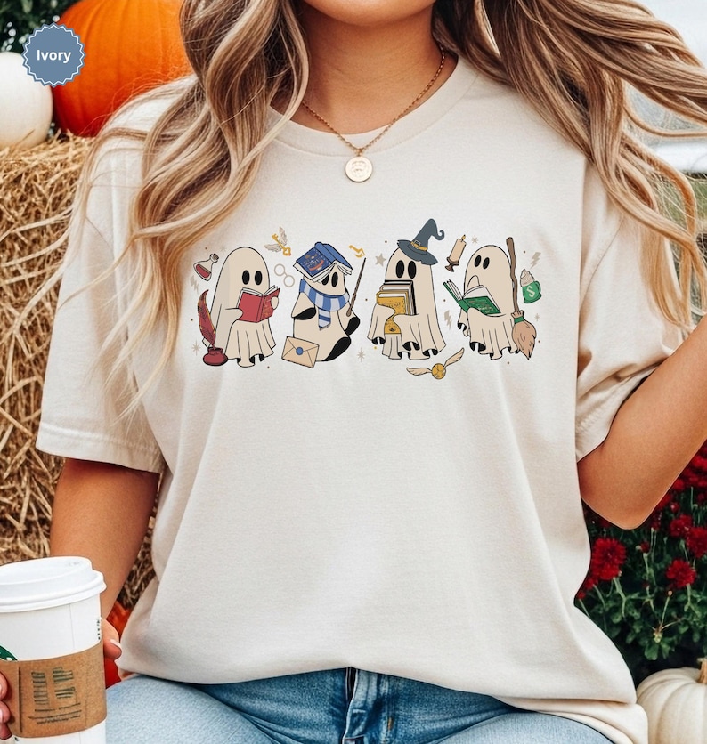 Halloween ghost shirt featuring four cute reading ghosts dressed as magical wizard characters with books, broomstick, owl, potion, and spooky season graphics on a cozy Halloween graphic tee.