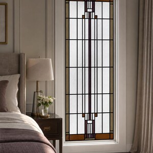 May include: A tall, rectangular window featuring a geometric stained glass design with a grid of black lead lines, clear textured glass panes, and accents of brown and deep purple glass blocks arranged in a symmetrical, vertical pattern.