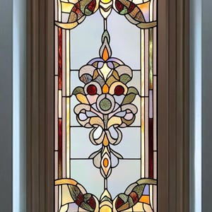 Op de afbeelding: Een rechthoekig glas-in-loodraam met een bruin houten frame. Het raam heeft een symmetrisch ontwerp met een centraal bloemmotief in geel, oranje, groen en rood. De achtergrond is lichtblauw.