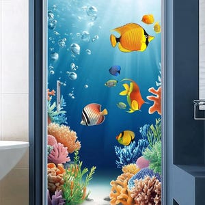 Könnte beinhalten: Eine Duschtür mit einer farbenfrohen Unterwasser-Szene mit Korallenriffen und tropischen Fischen. Die Fische sind orange, gelb, blau und rot. Die Korallen sind rosa, orange und grün.