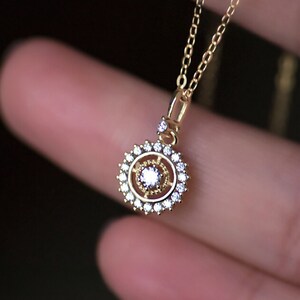 May include: A gold necklace with a round pendant featuring a central clear stone surrounded by smaller clear stones.