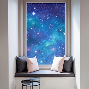 May include: A window seat with a view of a starry night sky. The window is framed by a light-colored trim, and the seat features gray cushions and decorative pillows in pink and gray. A small, black side table sits in front.