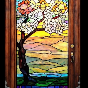 Puede incluir: Una ventana de vitrales que representa un árbol estilizado con flores rosas y amarillas sobre un fondo de puesta de sol. El árbol se encuentra frente a un paisaje de colinas onduladas y un río azul.