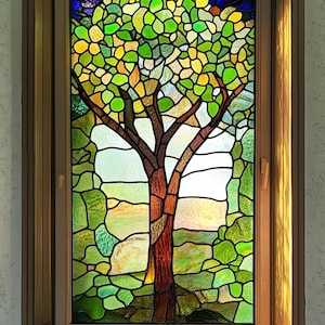 Puede incluir: Una ventana de vitrales que representa un árbol con hojas verdes y un tronco marrón. El árbol se coloca sobre un fondo de vidrio verde y azul.