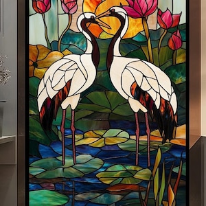 Puede incluir: Una ventana de vitral que representa dos grullas blancas de pie en un estanque con nenúfares. Las grullas se miran y tienen el cuello entrelazado. El fondo es una mezcla vibrante de azul, verde, amarillo y rojo.