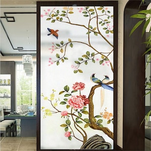 May include: A white background with a brown tree branch with pink flowers and green leaves. Two blue birds with long tails are perched on the branch. A single red bird is flying above the branch.