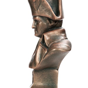 May include: A bronze bust of a man wearing a tri-cornered hat. The bust is on a square base.