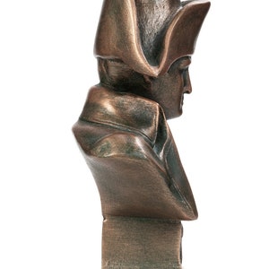 May include: A bronze bust sculpture of a man wearing a bicorne hat. The bust is on a square base.