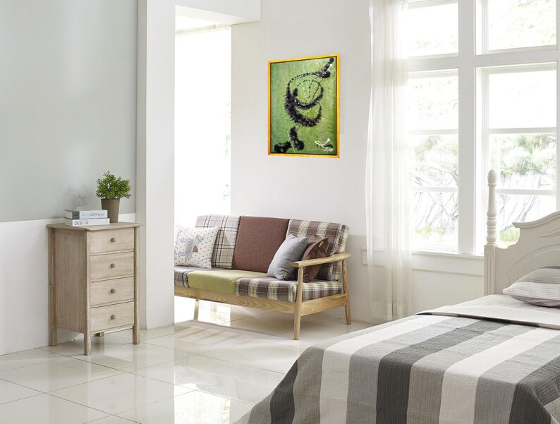 Pu&ograve; includere: Una cassettiera in legno chiaro con quattro cassetti in una camera da letto. Un divano con rivestimento a quadri &egrave; in primo piano. Un quadro incorniciato con un design astratto verde e nero &egrave; appeso al muro.