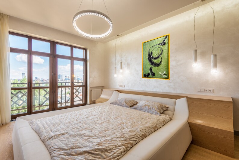 Pu&ograve; includere: Un letto bianco con un piumino beige e due cuscini in una camera da letto moderna con una grande finestra con vista sullo skyline della citt&agrave;. Un dipinto astratto verde e nero incorniciato &egrave; appeso al muro sopra il letto.