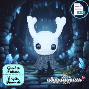 Puede incluir: Una figura blanca de ganchillo con grandes ojos negros y dos cuernos curvados. La figura tiene una capa gris y está sobre un fondo azul y gris con formaciones de cristal. La imagen incluye el texto "Crochet Pattern English Spanish".
