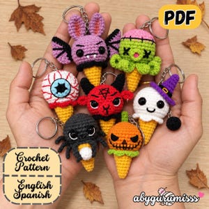 Puede incluir: Una colección de siete llaveros amigurumi de ganchillo con forma de conos de helado con temática de Halloween, que incluye un murciélago, un monstruo verde, un globo ocular, un diablo rojo, un fantasma con sombrero morado, una araña y una calabaza.