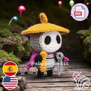 Puede incluir: Muñeca de ganchillo hecha a mano con sombrero amarillo, cara blanca y cuerpo gris. La muñeca tiene una capa rosa y sostiene un accesorio amarillo y gris. El fondo presenta una superficie de madera y follaje verde.