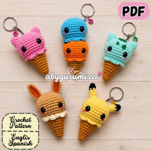 Puede incluir: Cinco llaveros de ganchillo con forma de cono de helado y diseños de personajes: un gato rosa, una doble bola azul y naranja, una criatura verde menta, un conejo marrón y un ratón eléctrico amarillo, cada uno con anilla y estrella.