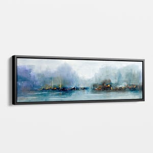 Può includere: Stampa artistica su tela panoramica di una scena costiera. L'opera presenta un porto nebbioso con barche ed edifici nei toni del blu, grigio e oro. Il dipinto è incorniciato in una cornice rettangolare nera.