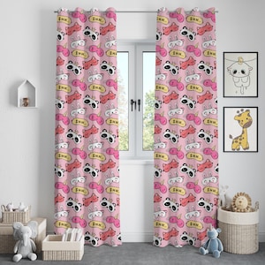 May include: Pink window curtains featuring a repeating pattern of cartoon sleep masks, including panda, unicorn, and bunny designs. Each mask has the word "SHH" printed on it. The curtains are hanging in front of a window.