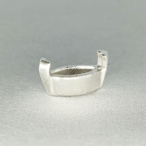 Puede incluir: Engaste de bisel de plata para una piedra preciosa, con una forma ovalada lisa y redondeada.