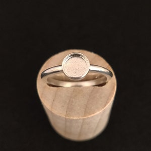 Puede incluir: Un anillo de plata con un engaste redondo. El engaste está vacío y listo para ser rellenado con una piedra u otro adorno.