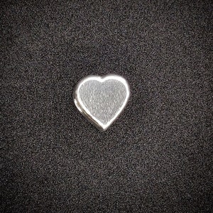 May include: A small silver heart charm with a textured surface.