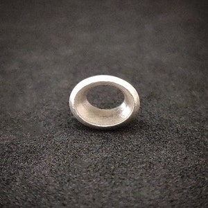 May include: A silver ring with a circular cutout in the centre. The ring is smooth and has a polished finish.