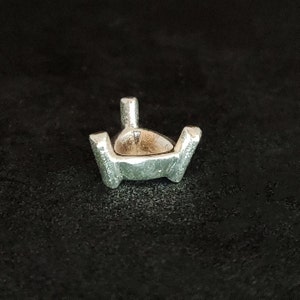May include: Silver prong setting for a gemstone. The setting has a claw-like design with four prongs.