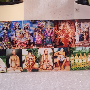 May include: A collage of 12 images featuring religious figures in various poses and settings. The images are arranged in a grid pattern and are printed on a rectangular surface. The images are colorful and vibrant, and the figures are depicted in a variety of traditional Indian clothing.