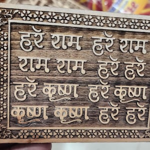 May include: A wooden plaque with a carved border and the text "हरे राम हरे राम राम राम हरे हरे हरे कृष्ण हरे कृष्ण कृष्ण कृष्ण हरे हरे" in Hindi.