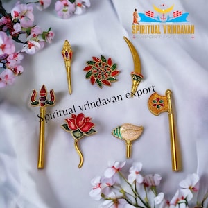 Puede incluir: Un conjunto de nueve iconos religiosos de metal dorado con detalles de esmalte de colores. Los iconos representan diversas deidades y símbolos hindúes, incluyendo un tridente, una flor de loto, una concha, una espada, un hacha y una rueda.