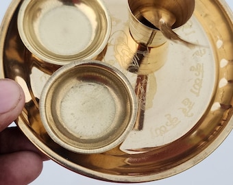 May include: A gold metal tray with three small bowls and a cup. The tray has an inscription in a foreign language.