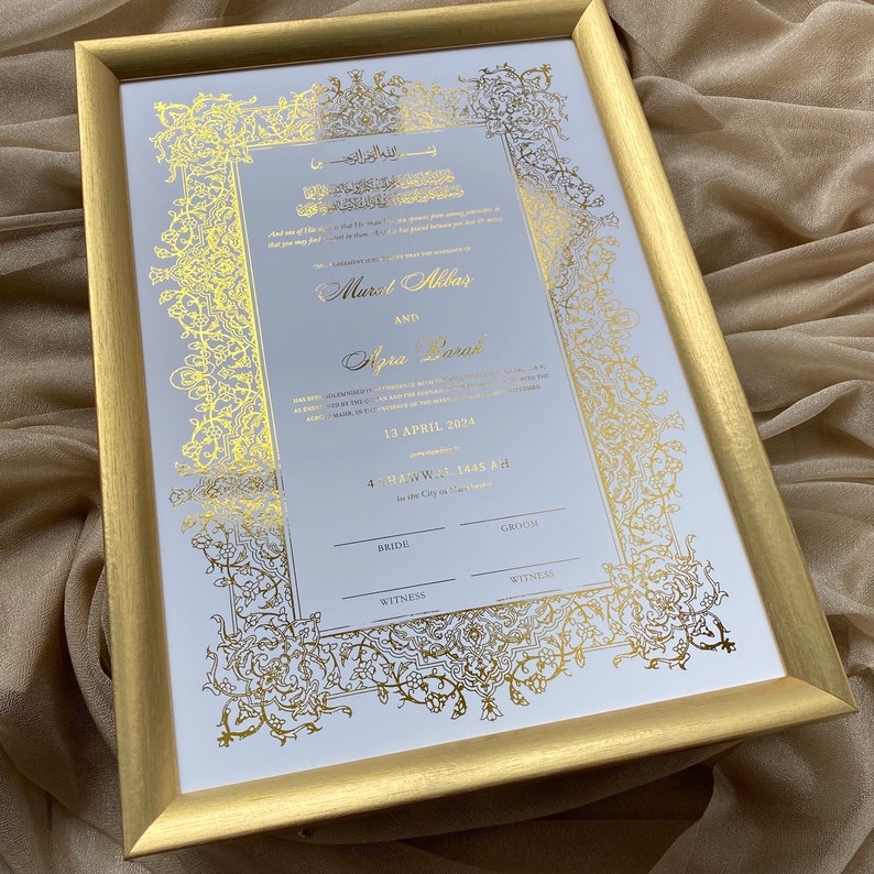 May include: A white wedding invitation with gold calligraphy and floral designs. The invitation includes the names "Murat Akbar" and "Afra Darak" and the date "13 April 2024".