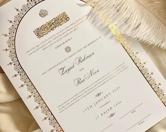 Könnte beinhalten: Eine weiße Heiratsurkunde mit goldener Kalligraphie und verzierten Rändern. Die Urkunde besagt "Diese Urkunde bescheinigt, dass die Ehe von Layad Rahman und Rea Noor geschlossen wurde." Das Datum der Hochzeit ist der 17. Januar 2025, entsprechend dem 17. Rajab 1446.