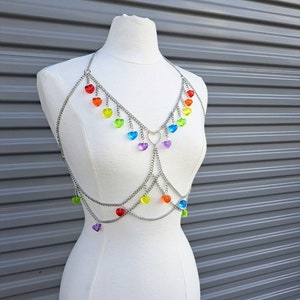 Puede incluir: Una pieza de joyería de cuerpo de cadena plateada con dijes de corazón de colores arcoíris. La cadena está en capas y tiene un dije en forma de corazón en el centro.