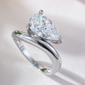 May include: A silver ring with a pear-shaped diamond set in a twisted band.