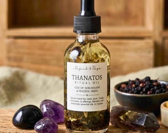 May include: A clear glass dropper bottle labeled Thanatos Ritual Oil, God of Non-Violent & Peaceful Death, containing botanical oil. Surrounded by two purple amethyst stones, one black stone, a small bowl of dark berries, and dried herbs.