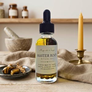 May include: A clear glass bottle of "Master Root Ritual Oil" with a black dropper top. The label reads "Magick & Sage". The bottle sits on a wooden table next to a candle in a brass holder, a small dish of stones, and a mortar and pestle.