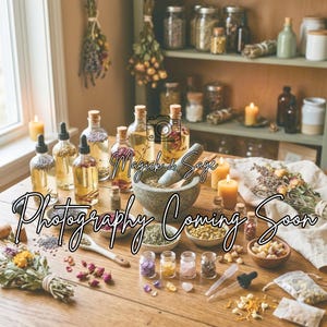 May include: A wooden table displays apothecary items, including glass bottles with cork stoppers, a mortar and pestle, and small jars filled with herbs and crystals. The text "Magick & Sage Photography Coming Soon" is overlaid on the image.